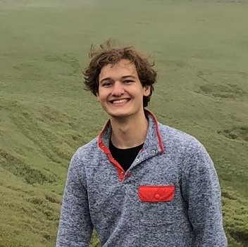 A portrait of the author in a mossy field